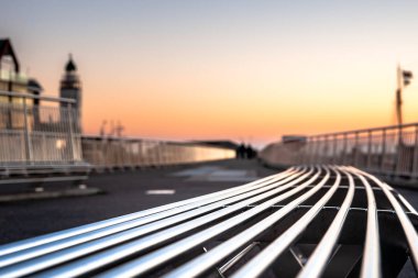 Modern boş demir tezgah ile eğri şekiller bir Bulvarı boyunca ya da bir parkta. Alüminyum renkler ve deniz feneri arka arka plan bulanık