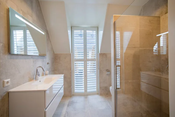 Architecturally built bathroom with luxury tiling, white shutter
