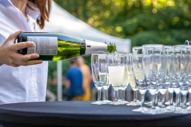 Şampanya bardakları bir katip tarafından dökülen kabarcıklar ile Şarap şişesi