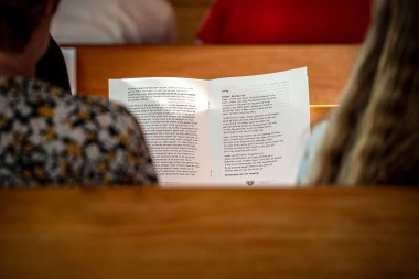 Poeple yumuşak ile kilisede ahşap bankta ibadet şarkıları söylüyor