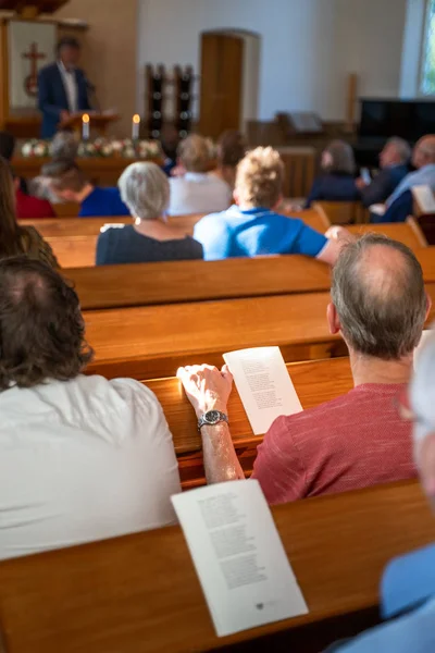 Poeple singing worship songs at wooden bench in church with soft