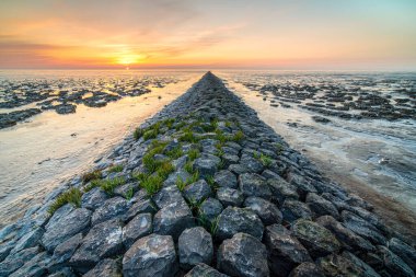'Dalgalar çekildiğinde' çamurlu düz 'manzaralı dramatik günbatımı gökyüzü altında bulutlarla