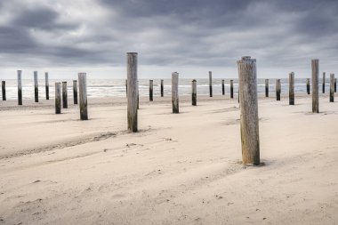 Petten (Hollanda) plajında tarihi bir sel anıtı. Deniz dalgaları ve fırtınalı bulutlarla uzun pozlu fotoğraf