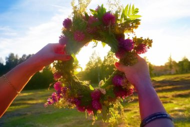 Yaz ortası meşesi ve çiçek çelengi sarı günbatımı ışığında. Eski Letonya kültür geleneği LIGO. Letonya 'da yaz dönümü kutlaması.