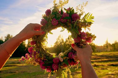 Midsummer Oak and flower wreath in yellow sunset light. Old Latvian culture tradition LIGO. Midsummer night celebrating in Latvia. clipart