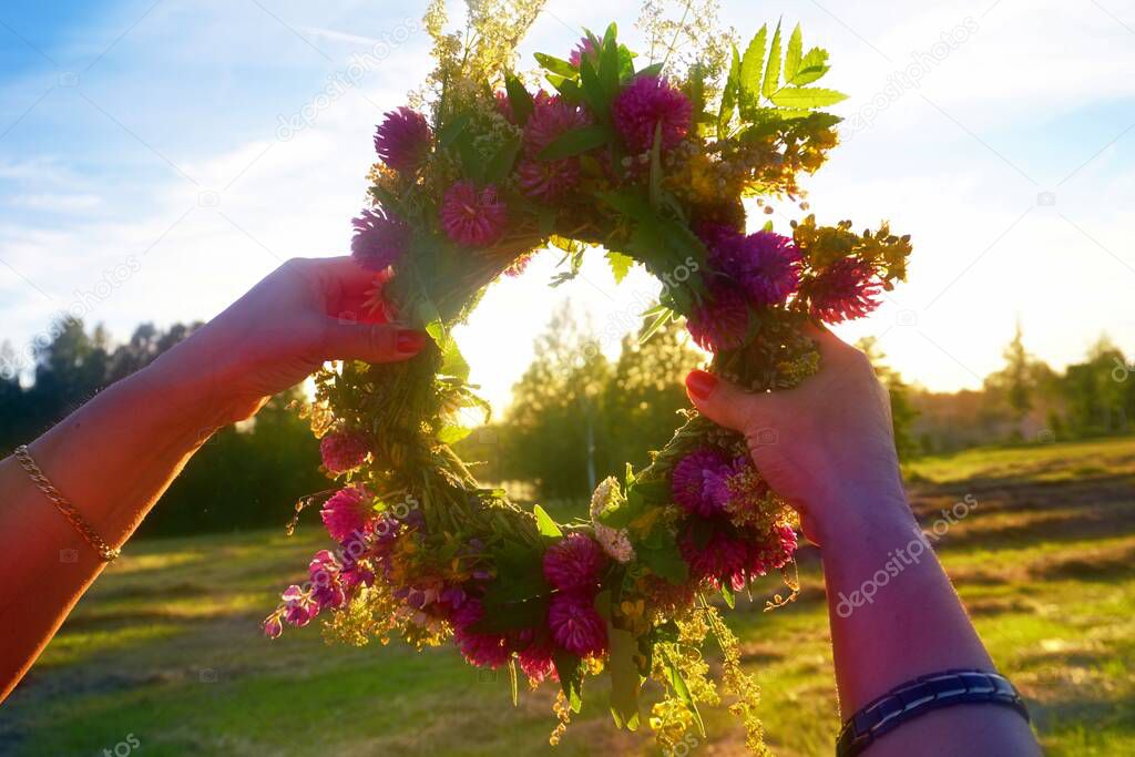 Midsummer Oak and flower wreath in yellow sunset light. Old Latvian culture tradition LIGO. Midsummer night celebrating in Latvia.
