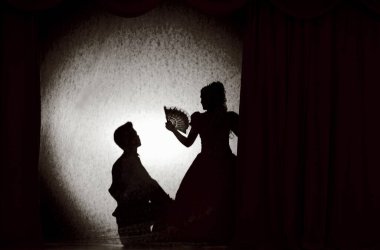 Riga, Letonya 22 Ekim 2011: Ortaçağ kostümlü insanlar sahnedeki gölgeler tiyatrosunda renkli perdelerle. Aşk üçgeninin teması