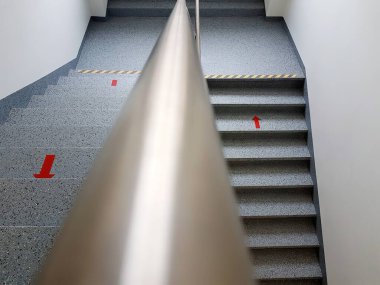 Çok katlı bir evin merdiven boşluğunda kırmızı ok işaretli, üst manzaralı.