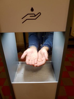 Kadın elleri otomatik dezenfekte makinesinin altında Coronavirus 'un yayılmasını önlemek için.