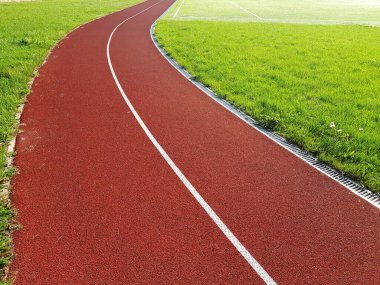 Spor stadyumunda beyaz çizgileri olan kırmızı koşu bandı. Stadyumda kırmızı koşu izleri var. Boş spor stadyumu. 