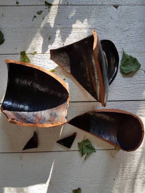 Beyaz tahta bir arka planda kırılmış kil bardak.