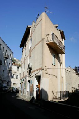 Beyaz evler, tuğla pencereler ve yeşil ağaçlarla geleneksel Sardunya şehir manzarası