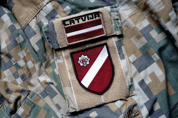 Latvian flag on the military khaki texture background. Latvian flag on army  uniform, military concept