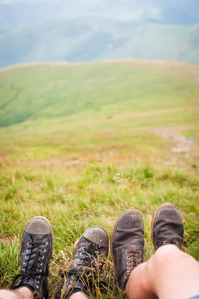 Travelers\' feet on the green grass in Carpathian Mountains, Ukraine