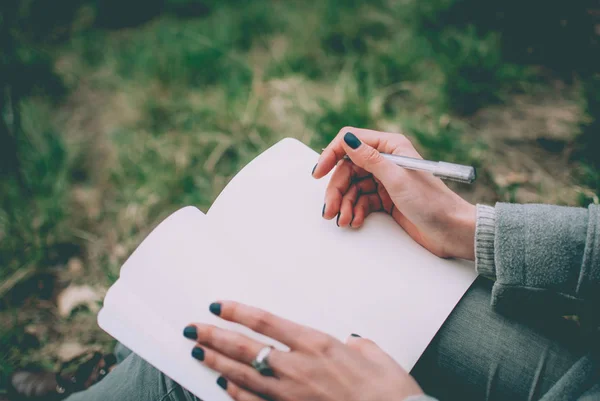 Chica Sentada Una Hierba Verde Primavera Anotando Sus Pensamientos Cuaderno —  Fotos de Stock