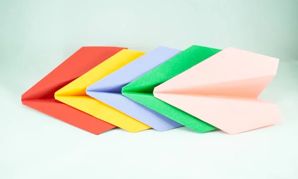 Red Paper Plane Leading Green Blue Peachy Yellow Ones White — Stock Photo, Image