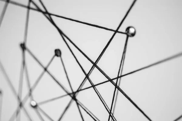 Blurred defocused background. Abstract concept (idea) of network, social media, internet, teamwork,  communication abstract. Thumbtacks linked together by red thread. Isolated. Entities connected.