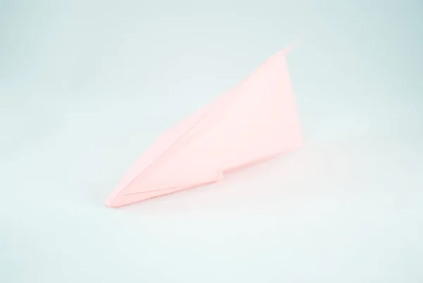 Pink (peachy) paper plane on a white background, isolated. Concept (idea) of airlines, freedom, leadership, success,  and creativity. Close-up