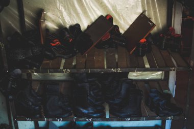 Acil servis botları çalışıyorum. Doğal afetler, ekolojik felaketler, silahlı çatışma, yangınlar ve diğer durumlarda acil durumlarda kullanılan ağır siyah deri ayakkabı. Depolama birimindeki ahşap rafta duran çizmeler.