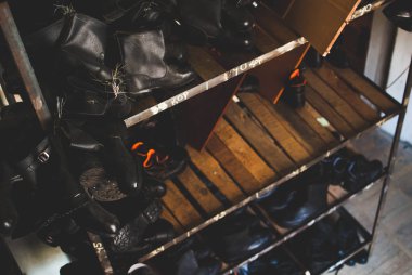 Acil servis botları çalışıyorum. Doğal afetler, ekolojik felaketler, silahlı çatışma, yangınlar ve diğer durumlarda acil durumlarda kullanılan ağır siyah deri ayakkabı. Depolama birimindeki ahşap rafta duran çizmeler.