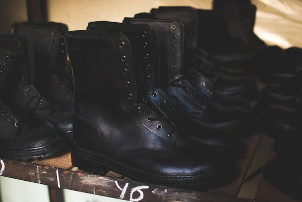 Emergency services work boots. Heavy black leather shoes used in cases of natural disasters, ecological catastrophes, armed conflicts, fires, and other cases of emergency. Boots standing on the wooden shelf in the storage.