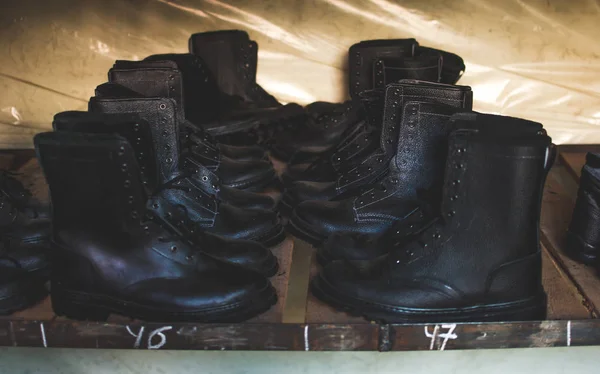 Emergency services work boots. Heavy black leather shoes used in cases of natural disasters, ecological catastrophes, armed conflicts, fires, and other cases of emergency. Boots standing on the wooden shelf in the storage.