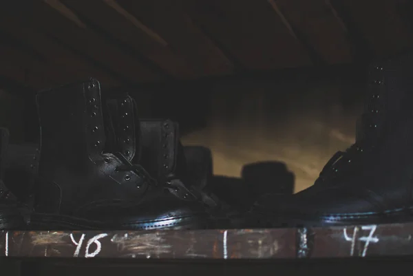 Emergency services work boots. Heavy black leather shoes used in cases of natural disasters, ecological catastrophes, armed conflicts, fires. Boots laying on the wooden shelf in the storage.