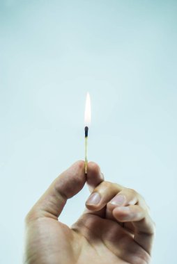 Işıklı bir maç parmaklar beyaz arka plan üzerinde tutan elini. Portre