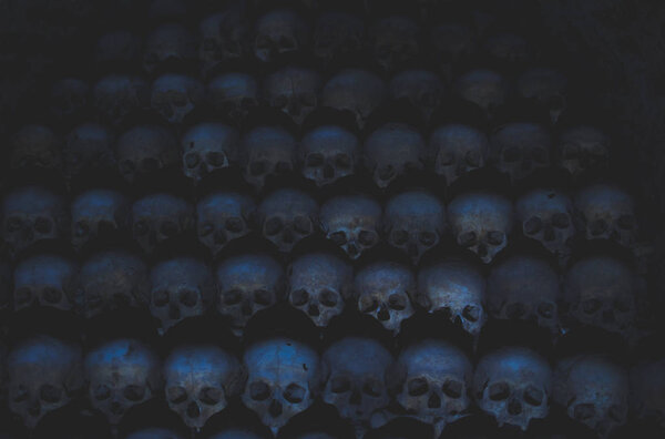 Collection of skulls covered with spider web and dust in the catacombs. Numerous creepy skulls in the dark highlighted by candle light. Abstract concept symbolizing death, terror, and evil. Vintage retro colors