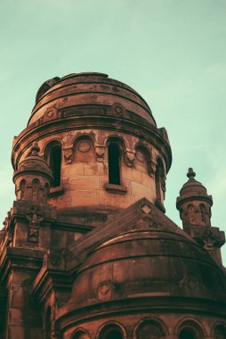 Soluk depresif heykelleri, anıtları ve mezar taşları üzerinde güneşli sonbahar aftetnoon mezarlığın. Kırmızı alacakaranlık ağaçları kapsayan