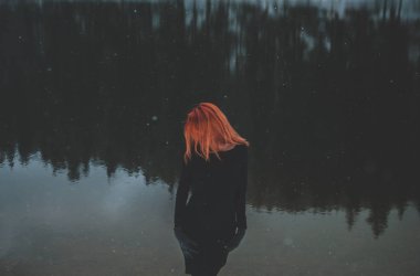 Yakışıklı Kızıl saçlı kız aşağı bakıyor. Onun saçının düşen kar taneleri. Muhteşem gölgeli siyah dağ gölü. Karpat Dağları'nın rüya gibi kış manzarası.