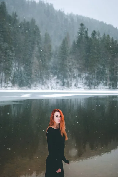 Красивая Рыжая Девушка Смотрит Падающие Волосы Снежинки Великолепное Тенистое Озеро — стоковое фото