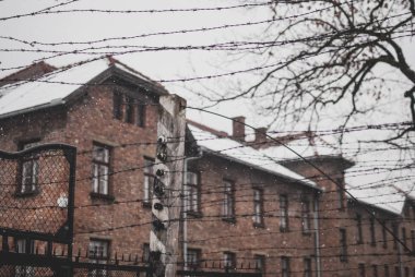 Oswiecim, Polonya - 16 Şubat 2018: dikenli tel çit karşı kırmızı tuğla ev toplama kampı Auschwitz ünlü arch yakınındaki