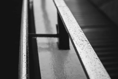 Metal korkuluk merdiven tarafından üzerinde yağmur damlaları Close-up. Gri bulutlu gökyüzü yansımasıdır. Ocak Ayı Hava yağmurlu. Metro İstasyonu, Berlin, Almanya. Siyah ve beyaz