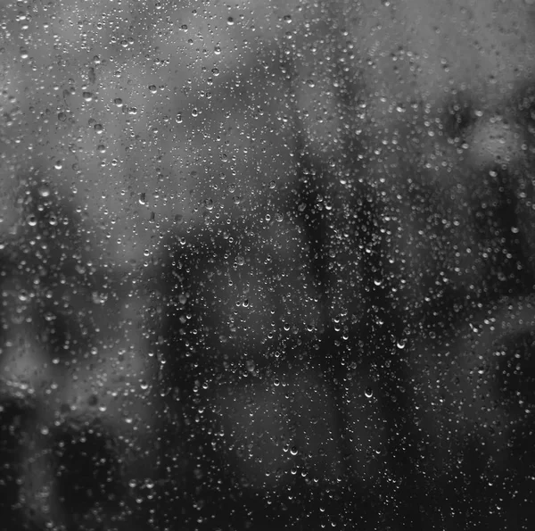 窗口玻璃上的雨滴的方形特写镜头 背景模糊的办公灯 — 图库照片