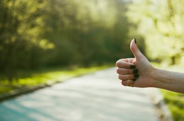 Kız (gibi) jest güneşli yeşil arka plana karşı bir thumps uyduruyor. Otostop, seyahat, turizm ve macera kavramı