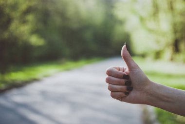 Kız (gibi) jest güneşli yeşil arka plana karşı bir thumps uyduruyor. Otostop, seyahat, turizm ve macera kavramı