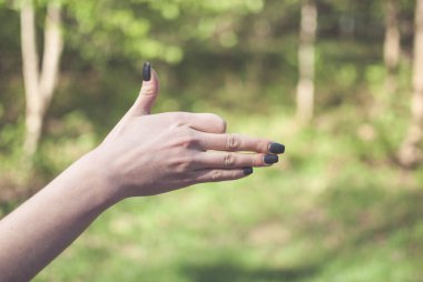 Kız el jest güneşli yeşil arka plana karşı bir köpek yapma. Vintage renkleri
