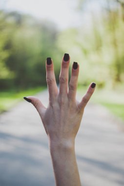 Bir sayı beş (5) jest güneşli yeşil arka planı gösteren kız.