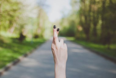 Parmak hareketi güneşli yeşil arka planı gösteren kız geçti.