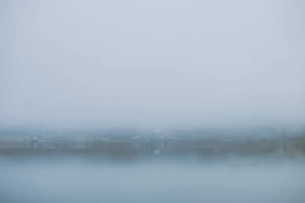 神秘的山湖在初春的早晨 从覆盖水面的诡异浓雾中可以看到湖对岸的小屋和别墅 — 图库照片