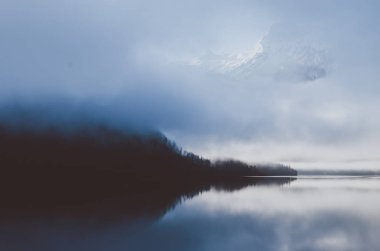Avusturya Alplerinde görünümü hoş manzara. Sabah erken Nehri mavi günbatımı sis ile kaplı. Bulutların üzerinde görülen dağ.