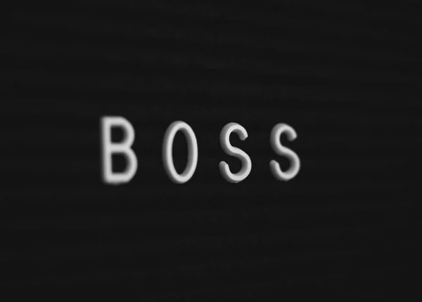 Word boss written on the letter board. White letters on the black background