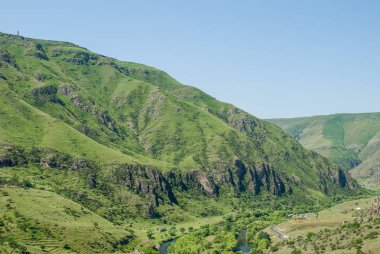 Gürcistan'daki muhteşem güneşli manzara. Kayalık yeşil dağlar ve derin mavi gökyüzü. Çim tepeler kapsayan