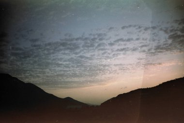 Mtsheta, Gürcistan Kafkasya dağlarında güzel kırmızı günbatımı. Siyah gölgeli dağlar ve bulutlu gökyüzü. Sinema film fotoğraf