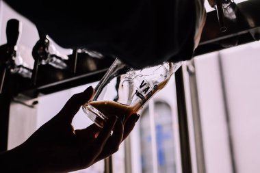 Lviv, Ukrayna - 4 Eylül 2018: Siluet koyu bira zanaat bira barda bir bardak dökülen bir kız. Yerel pub. Arka plandaki parlak bira musluklar