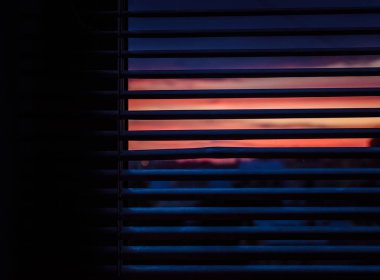 Atmospheric colorful sunset seen through the window jalousie. Deep shadows. Dreamy evening skies. clipart