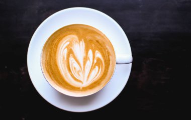 Cappuccino bir soyut bir kahverengi kahve köpük üzerinde çizim ile beyaz fincan. Zarif kahve sanat. Kavram arka plan kafe, dinlenme, eğlence ve romantik ayarlar. Yukarıdan görüntüleyin. Derin siyah arka plan