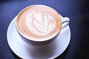 Cappuccino bir soyut bir kahverengi kahve köpük üzerinde çizim ile beyaz fincan. Zarif kahve sanat. Kavram arka plan kafe, dinlenme, eğlence ve romantik ayarlar. Derin siyah arka plan