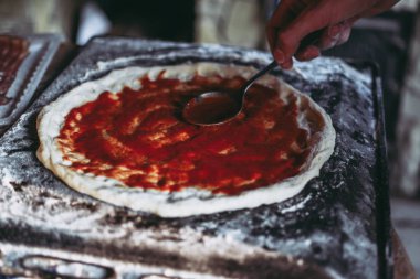 Oyuncu ham pizza hamuru domates soslu Gresler. Lezzetli biberli pizza. Ev yapımı pizza hazırlık süreci.